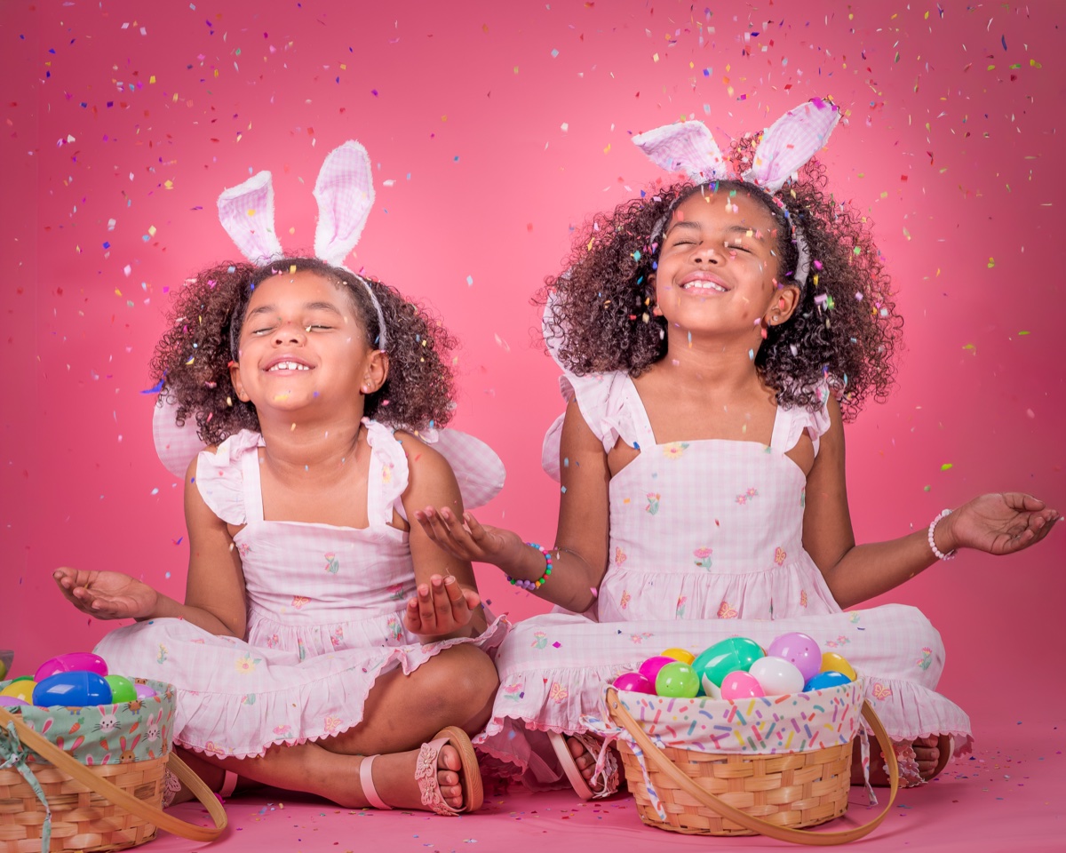 Twin sisters with bunny ears and confetti, pink backdrop — Austin family photographer