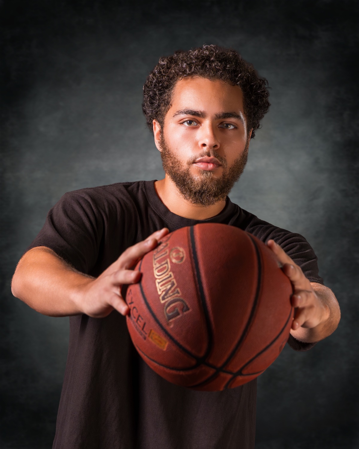 Confident basketball player holding the ball forward in studio — Austin athletic & senior portrait photographer