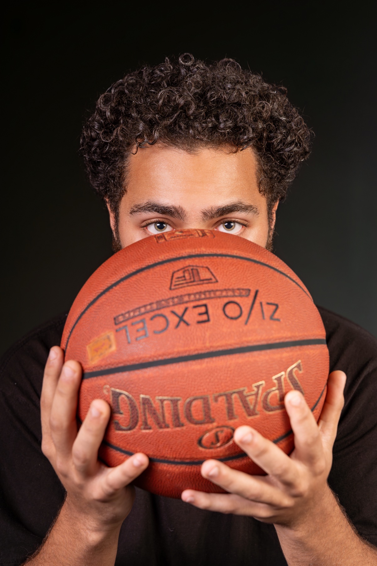 Athletic studio portrait — basketball player with eyes over the ball, dramatic light — Austin senior & sports portrait photographer Reinier Lop