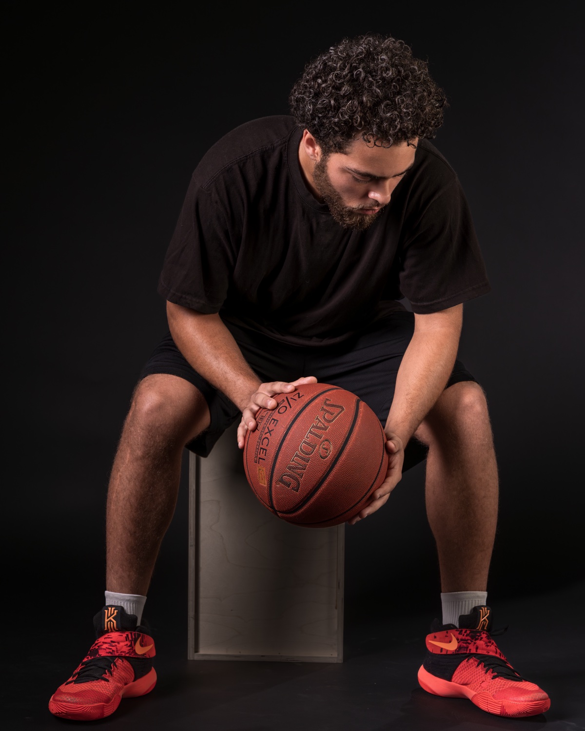 Moody seated studio portrait of a basketball player on dark backdrop — Austin editorial portrait photographer
